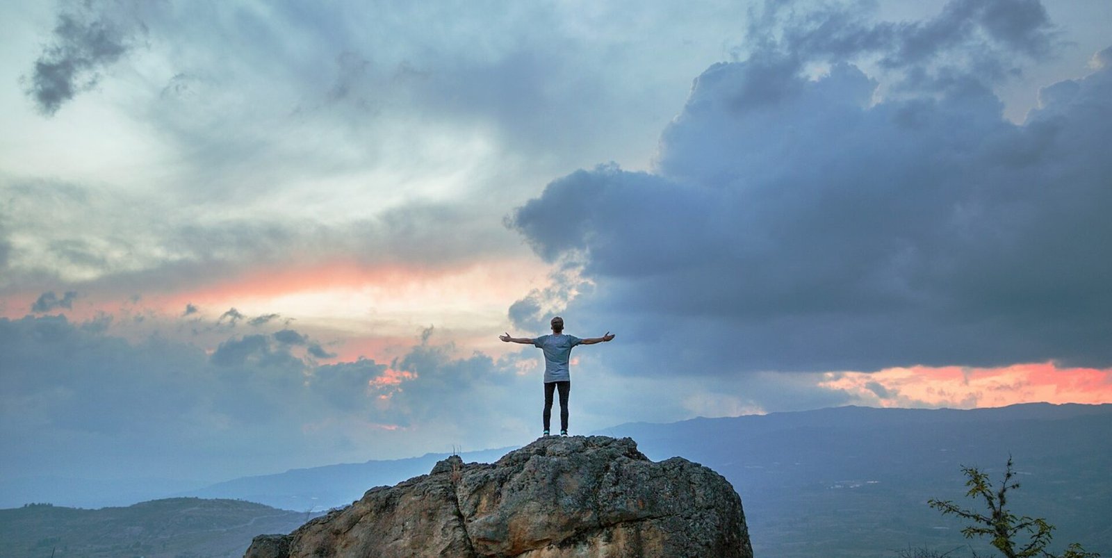 man standing on top of rock mountain during golden hour